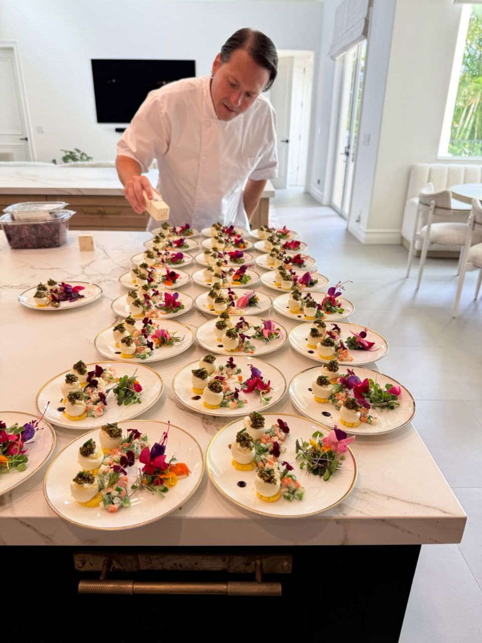 Chef Nash plating caviar canapés on a marble kitchen island